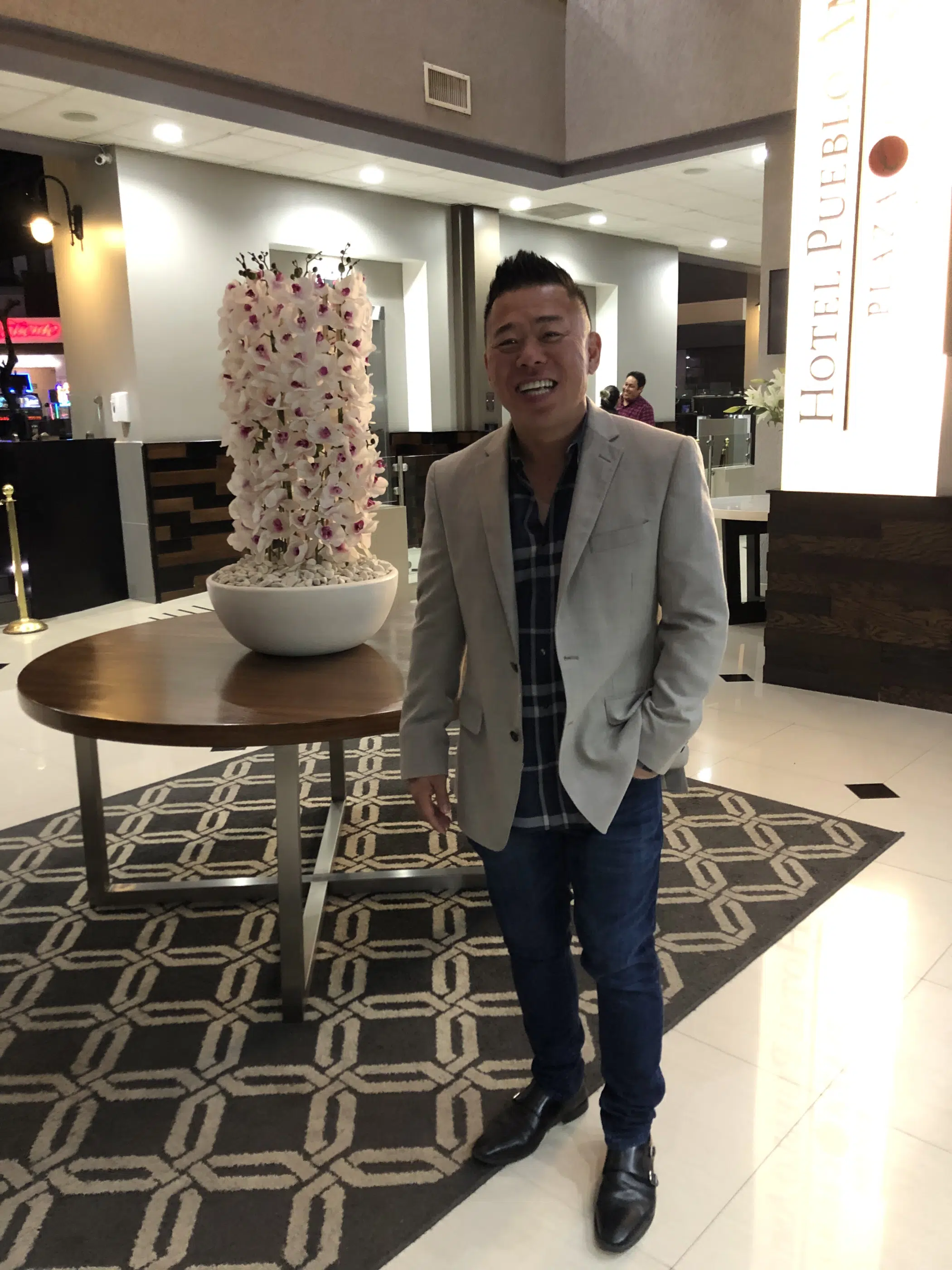 Kwan standing confidently in a hotel lobby with a stylish interior.