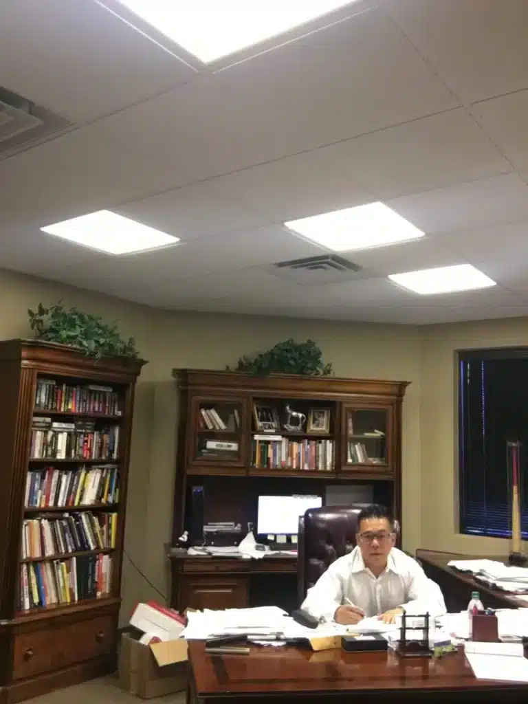 Kwan at his office desk surrounded by bookshelves and work materials.